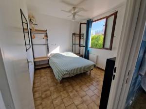 een kleine kamer met een bed en een raam bij Agréable Appartement in La Londe-les-Maures