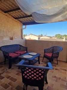 een patio met 4 stoelen en tafels en een dak bij Agréable Appartement in La Londe-les-Maures