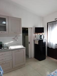 a kitchen with a black refrigerator and a microwave at Casa vacanza Ligustro appartamento il gabbiano in SantʼAntìoco