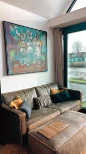 a living room with a brown couch and a window at Tiny house of Picasso in Warmenhuizen