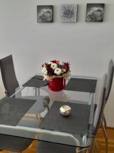 une table à manger en verre avec des chaises et un vase avec des fleurs dans l'établissement ARS VIP Apartment, à Novi Sad