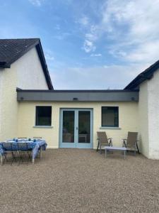 a patio with a table and chairs in front of a house at Harry's Cottage in Aghanloo