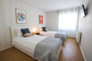 two beds in a small room with a window at Just Like Home - Moledo Waves in Moledo