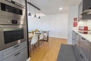 a kitchen with a dining table and a kitchen with a stove at Just Like Home - Moledo Waves in Moledo