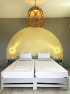 2 Betten in einem Zimmer mit Kronleuchter in der Unterkunft Agnadi Syros Beachfront Studios & Rooms in Megas Gialos - Nites