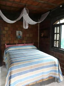1 dormitorio con 1 cama con manta de rayas azul y blanco en Pousada do Oasis, en Morretes