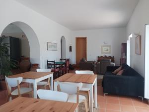 una sala de estar con mesas de madera y sillas blancas. en Casa da Osga, en Tavira