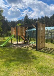 un parco giochi in legno con scivolo in un cortile di Przylesie Dom na Roztoczu 