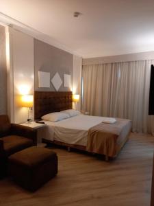 Habitación de hotel con cama y silla en International Airport Flat - Guarulhos quarto 1267, en Guarulhos