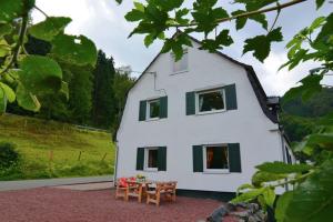 a white house with green shuttered windows and a table at Olsberg Elpe in Elpe