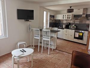 a kitchen with white cabinets and a table and chairs at La suite du beffroi in Malaucène