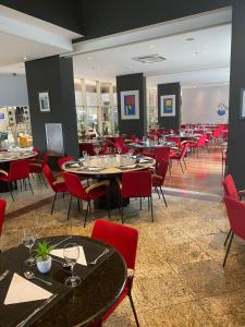 a restaurant with tables and chairs and red chairs at International Airport Flat - Guarulhos quarto 1267 in Guarulhos