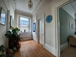 a living room with a clock on the wall and a hallway at Beautiful Victorian Seaside House in Clevedon