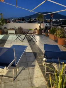 eine Terrasse mit Stühlen, Tischen und einem Sonnenschirm in der Unterkunft B&b L’Attico e la Ballata in Brusciano