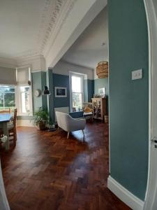 uma sala de estar com um sofá e uma cadeira num piso de madeira em Beautiful Victorian Seaside House em Clevedon