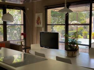 a living room with a table and a tv and windows at Maison AdriAnna in Vedène