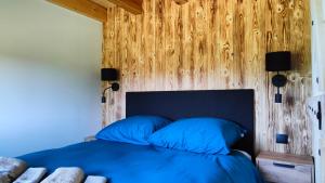sypialnia z niebieskim łóżkiem i drewnianą ścianą w obiekcie Na Zaciszu w mieście Cierzpięty