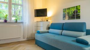 a blue couch in a living room with a tv at Apartament Ski Sudety Karpacz in Karpacz