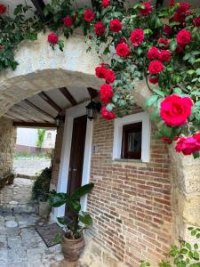 un edificio de ladrillo con rosas rojas creciendo en él en La casetta di Sofi, en Petralia Soprana