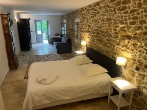 um quarto com uma cama e uma parede de pedra em Domaine de la Calamande em Grillon