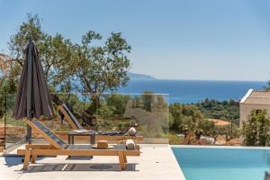 a villa with a swimming pool and an umbrella at Luxury Stone Villas Kefalonia in Trapezaki