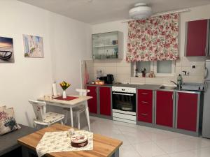 a kitchen with red cabinets and a table and a dining room at APARTMENT ROLEX -near the port Dubrovnik in Dubrovnik
