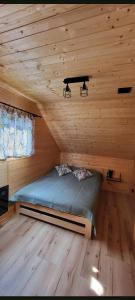 a bed in a cabin with a wooden ceiling at Domek w sercu Kaszub in Dziemiany