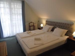 a bedroom with a large bed with white sheets and pillows at Millennium Villa in Keszthely