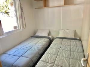two beds in a small room with a window at Tiny House, Mobilhome 6 personnes au Port de Vendres plage in Vendres