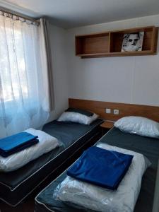 two twin beds in a room with a window at Mobil home emplacement 38a in Les Mathes