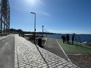 a group of people standing on a sidewalk next to the water at Top, cozy, lakeside, sauna and free indoor parking in Tampere