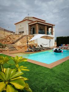 a house with a swimming pool with chairs and an umbrella at Villa al vent (lujo & relax) in Benitachell