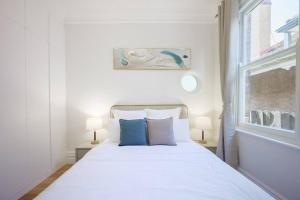 a white bed with two blue pillows in a bedroom at Cosy Federation Apartment Kirribilli 2 Bedroom #1 in Sydney