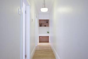 a hallway with white walls and a white kitchen at Cosy Federation Apartment Kirribilli 2 Bedroom #1 in Sydney