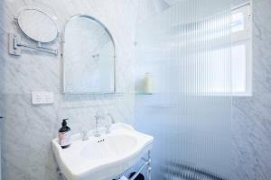Baño blanco con lavabo y espejo en Cosy Federation Apartment Kirribilli 2 Bedroom #1, en Sídney