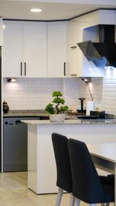 a kitchen with white cabinets and a counter with two chairs at Smile Suite Hotel in Çaycuma