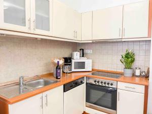 a kitchen with white cabinets and a sink and a microwave at Opera Residence in Budapest