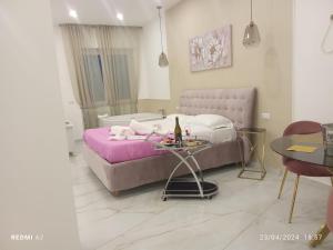 Un dormitorio con una cama morada y una mesa con una botella de vino. en Maison De luxe en Pompeya