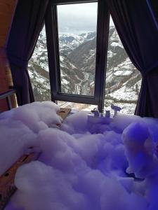 a snow covered bed with a view of a mountain at Puleri Suit Bungalow in Çamlıhemşin