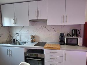 a kitchen with white cabinets and a sink and a microwave at Casa da Furna in Santo António