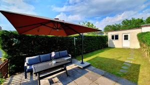 a bench with a red umbrella in a yard at Yucca cottage in Kendal