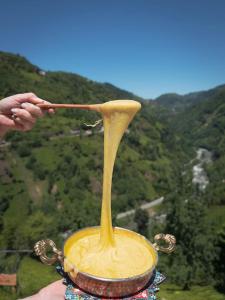 a person holding a spoon with a pot of yellow sauce at Puleri Suit Bungalow in Çamlıhemşin