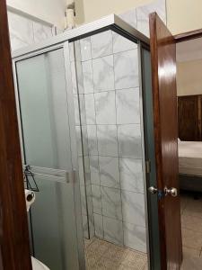 Una puerta de ducha de cristal en un baño con cama. en Casita Luz, en Juayúa