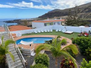 a house with a swimming pool and chairs and the ocean at Volcán de Sal in Villa de Mazo