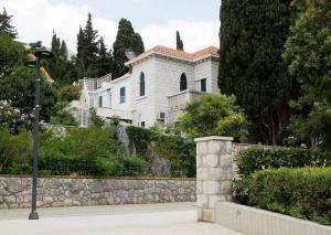 a white house on a hill with a stone wall at Beachfront Dubrovnik Villa in Dubrovnik