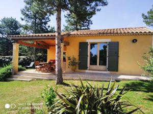a small yellow house with a patio at Proche Uzès petit gîte avec grande cuisine d'été et piscine in Saint-Siffret