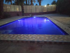 a swimming pool with blue lighting in a backyard at Bivouac Lot Of Stars in Ouarzazate