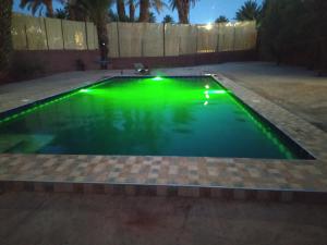 una piscina con luz verde en un patio trasero por la noche en Bivouac Lot Of Stars en Ouarzazate