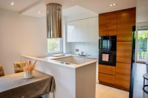 een keuken met witte kasten, een tafel en een wastafel bij SEApartment in Gdańsk