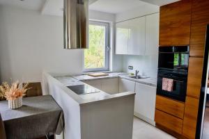 een witte keuken met een wastafel en een raam bij SEApartment in Gdańsk